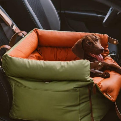 Dachshund resting in the orange green dog car booster seat bed fitted to a car seat