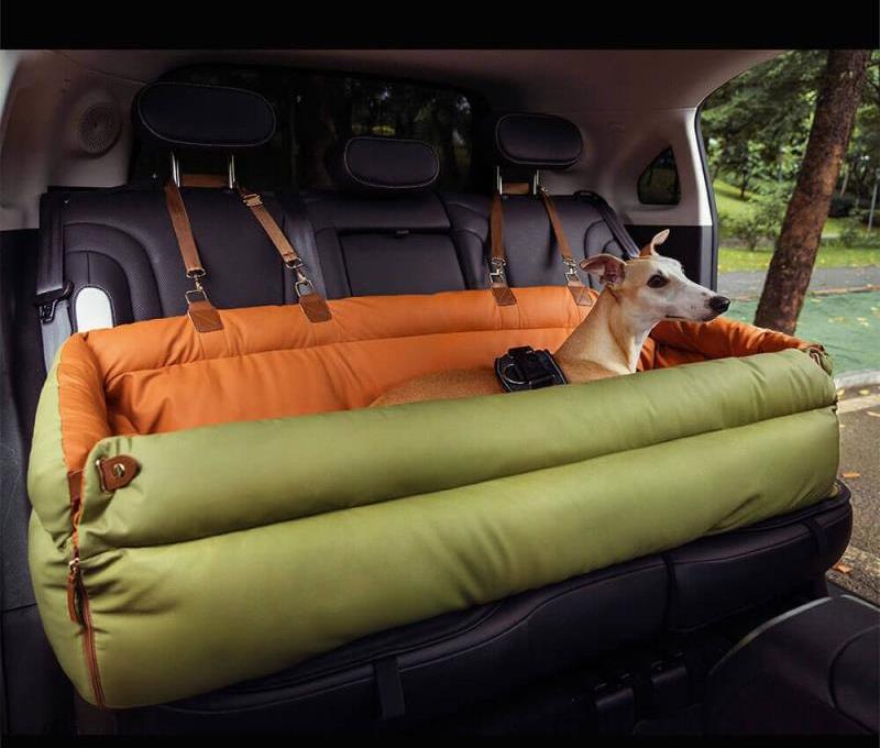 Orange green dog car booster seat bed in the back seat size, fitted across a rear bench with a dog lying in it